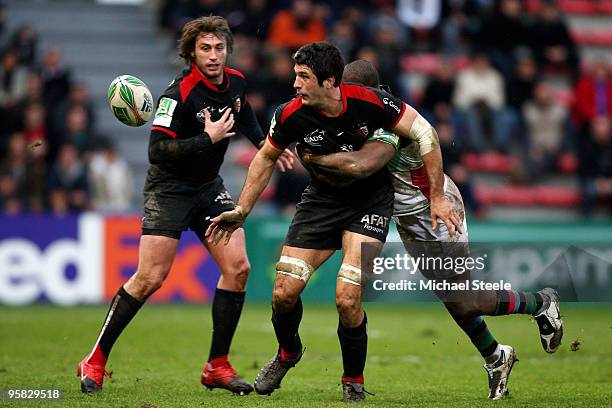 Jean Bouilhou of Toulouse offloads the ball despite the challenge of Ugo Monye as Maxime Medard looks on during the Toulouse v Harlequins Heineken...