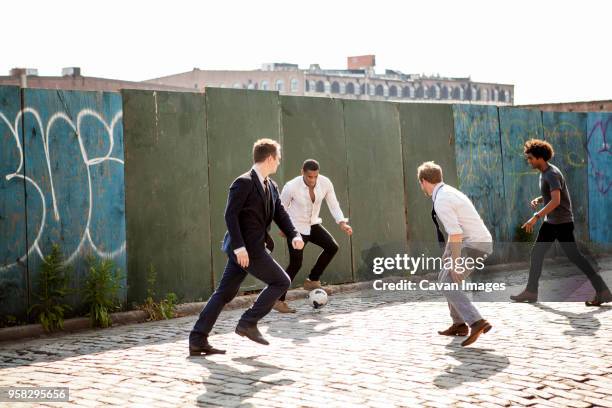 men playing soccer by wall on street - street football stock pictures, royalty-free photos & images