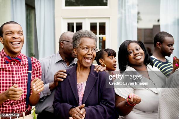 happy family and friends standing against house - familientreffen stock-fotos und bilder