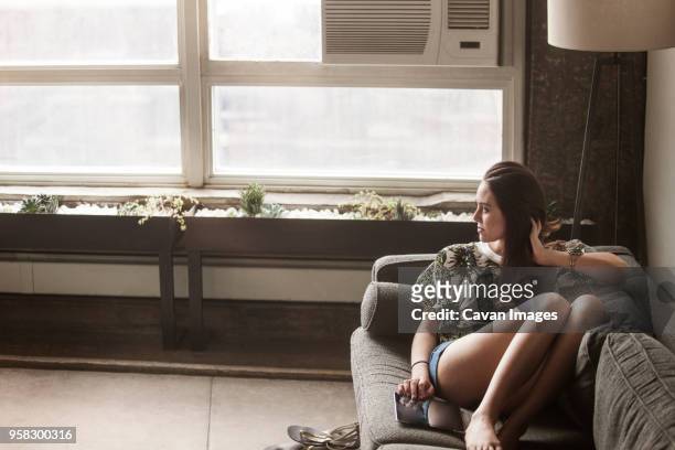 thoughtful woman with tablet computer sitting on sofa - cavan images stock pictures, royalty-free photos & images