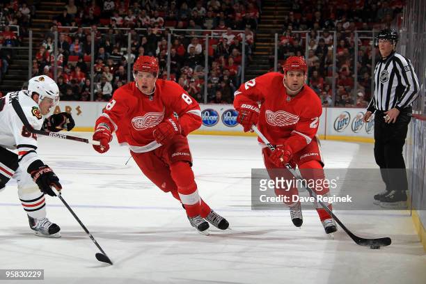 Brett Lebda of the Detroit Red Wings controls the puck as teammate Justin Abdelkader helps protect control from Tomas Kopecky of the Chicago...