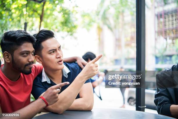 malaysian young men pointing and looking away - yongyuan stock pictures, royalty-free photos & images