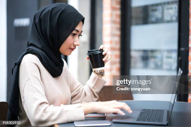 young muslim woman working on her laptop - yongyuan stock pictures, royalty-free photos & images