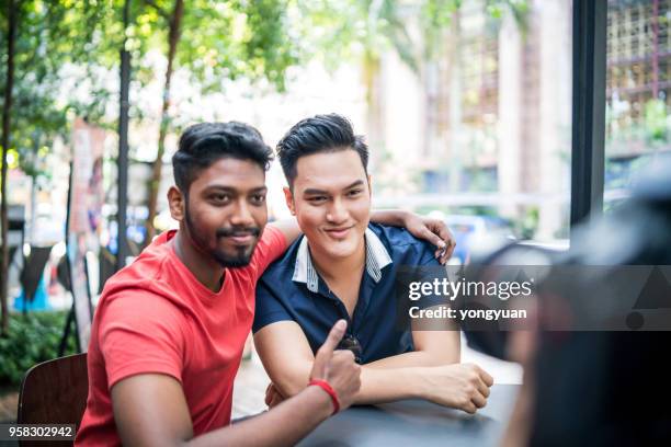 two cheerful malaysian young men being photographed - yongyuan stock pictures, royalty-free photos & images