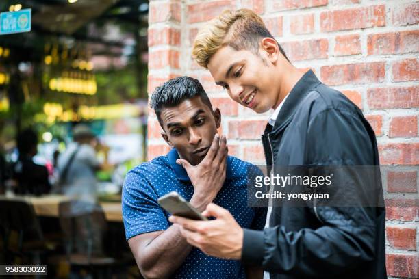 two young man looking at a smartphone - yongyuan stock pictures, royalty-free photos & images