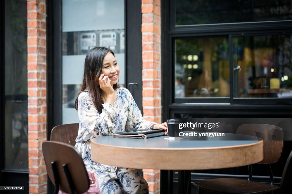 Young woman making a phone call at a cafe
