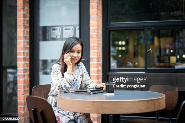 young woman making a phone call at a cafe - yongyuan stock pictures, royalty-free photos & images