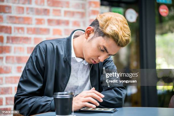 young malaysian man using a smartphone - yongyuan stock pictures, royalty-free photos & images