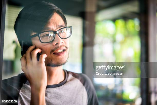 young malaysian man making a phone call - yongyuan 2018 stock pictures, royalty-free photos & images