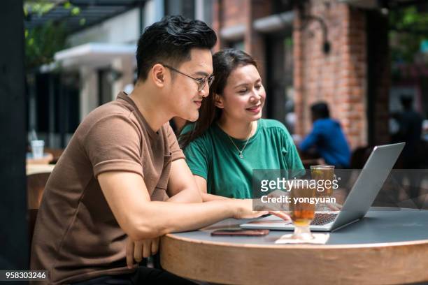 malaysian couple using a laptop together - yongyuan stock pictures, royalty-free photos & images