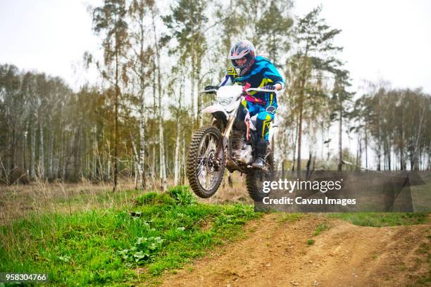female biker jumping with bike on field - women motorsport stock pictures, royalty-free photos & images