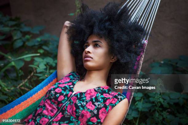 woman with frizzy hair looking away while lying on hammock - frizzy stock pictures, royalty-free photos & images