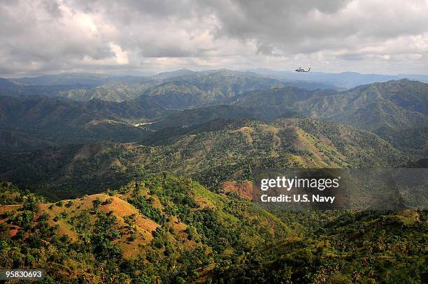 In this handout image provided by the U.S. Navy, A SH-60F Sea Hawk helicopter flies over the mountains of Haiti to deliver supplies to those affected...