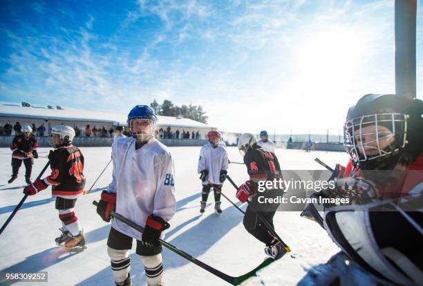 players playing ice hockey on sunny day - outdoor ice hockey stock pictures, royalty-free photos & images