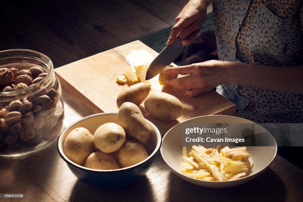 High angle view of woman cutting potatoes on cutting board at home