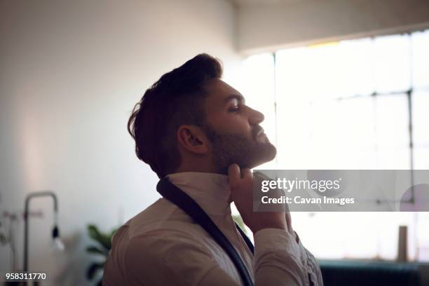 side view of man tying necktie - tied up stock pictures, royalty-free photos & images