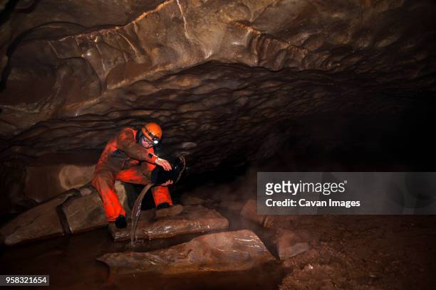 manual worker removing water from boot while sitting in cave - russia rain boots imagens e fotografias de stock