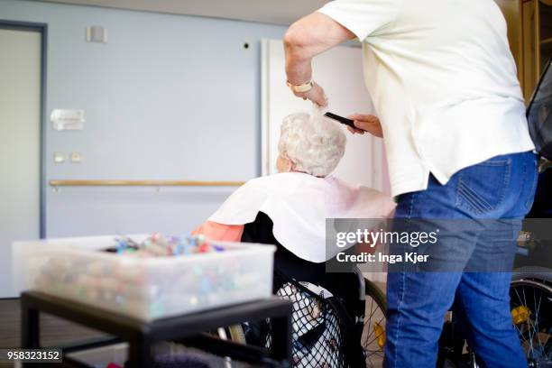 Barber dresses the hair of an old woman in a wheelchair in a nursing home on April 27, 2018 in Berlin, Germany.