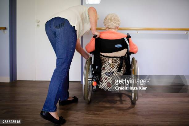 Caregiver talks to an old woman in a wheelchair standing in front of a wall on April 27, 2018 in Berlin, Germany.