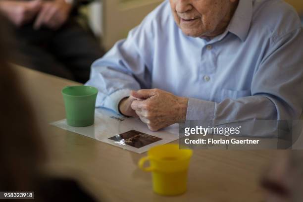 An old man sits at a table in a nursing home. Next to him is a plastic cup on April 27, 2018 in Berlin, Germany.