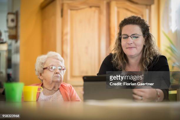 Caregiver of a nursing home shows an older woman something on a tablet on April 27, 2018 in Berlin, Germany.