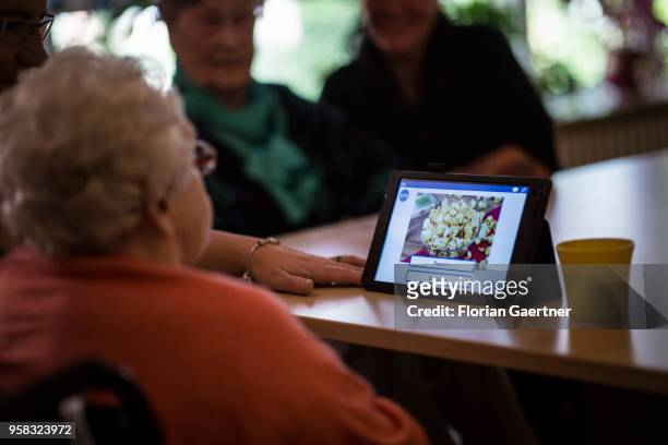 In a nursing home, an older woman plays a picture puzzle on a tablet on April 27, 2018 in Berlin, Germany.