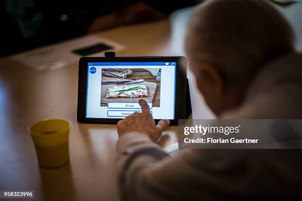 In a nursing home, an older man plays a picture puzzle on a tablet on April 27, 2018 in Berlin, Germany.