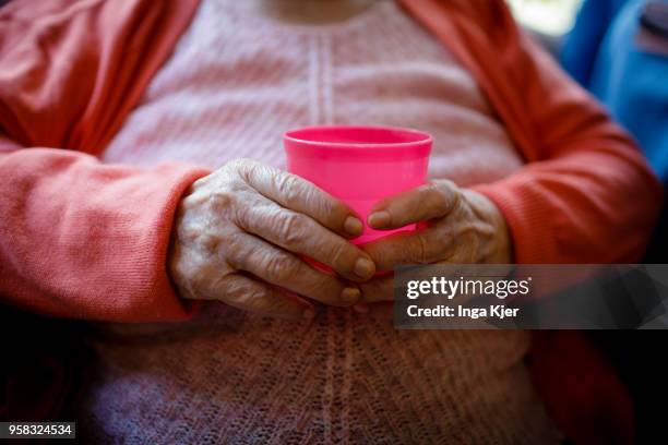 Resident of a nursing home holds a plastic cup in her hands on April 27, 2018 in Berlin, Germany.