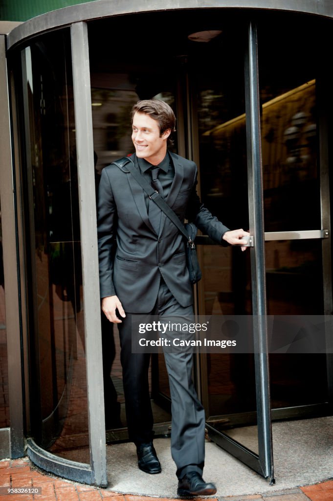 Happy businessman exiting from revolving door