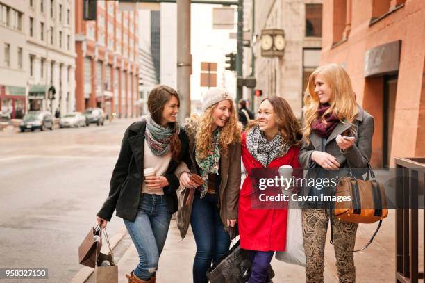 happy friends walking on sidewalk in city - four people foto e immagini stock