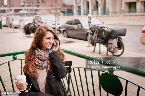 happy woman talking on phone while sitting at sidewalk cafe - co op city stock pictures, royalty-free photos & images
