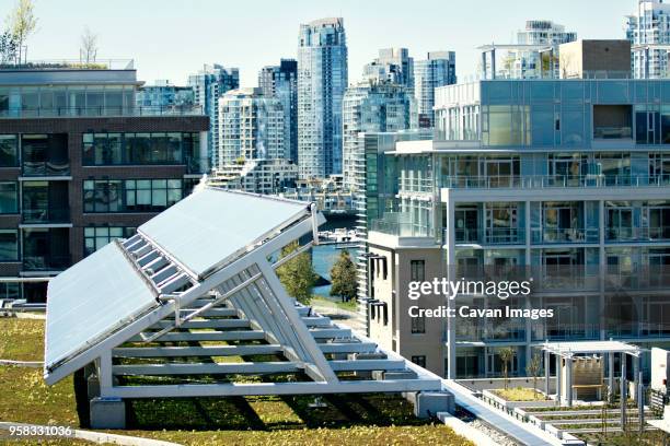 solar panel on field by buildings in city - energy efficient building stock pictures, royalty-free photos & images