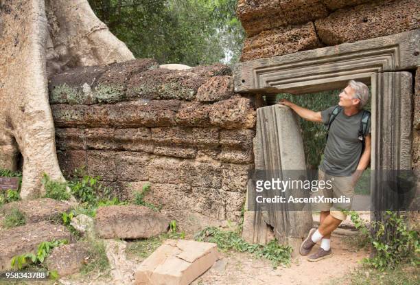 homem maduro explora ruínas de ta prohm - templo ta prohm - fotografias e filmes do acervo