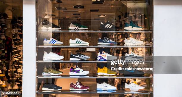 fashionable sneakers on display in shop window, london, uk - running shoe stock pictures, royalty-free photos & images