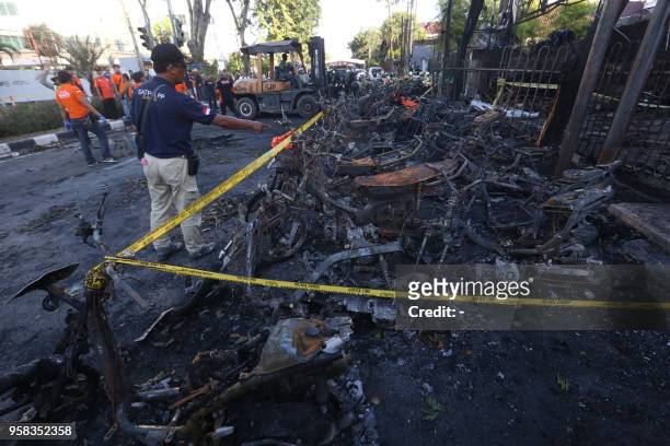 This picture taken on May 13, 2018 shows a man looking at burnt-out motorcycles following a bomb blast outside the Surabaya Centre Pentecostal Church...