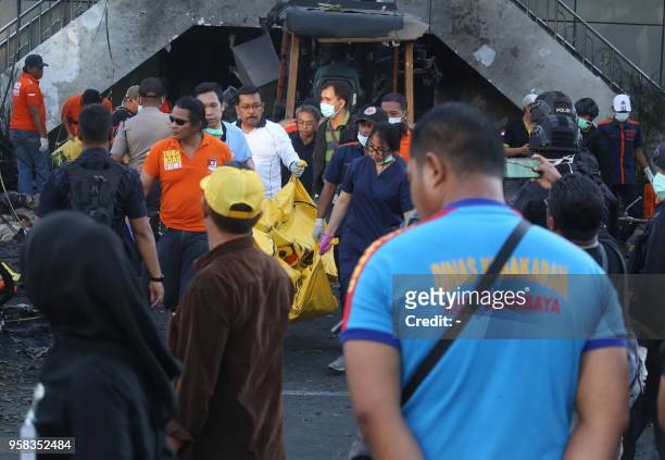 This picture taken on May 13, 2018 shows police taking away the remains of a victim in a body bag following a bomb blast outside the Surabaya Centre...