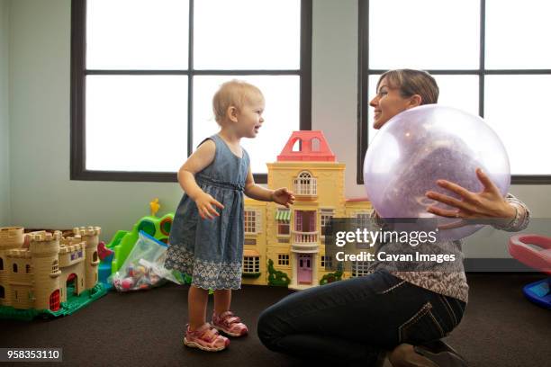 nanny and girl playing with ball at preschool - nanny smiling stockfoto's en -beelden