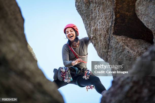 low angle view of happy woman rock climbing - clambering imagens e fotografias de stock