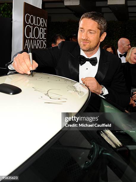 Actor Gerard Butler signs the Chrysler 300 Eco Style car for Stars for a Cause during the 67th annual Golden Globe Awards held at The Beverly Hilton...