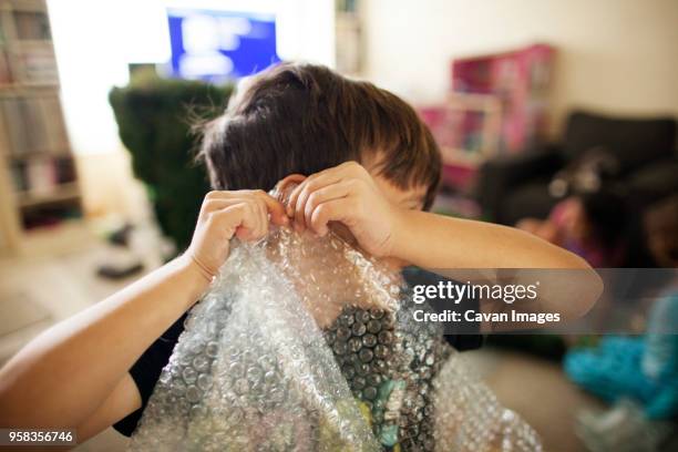 boy playing with bubble pack at home - luftpolsterfolie stock-fotos und bilder