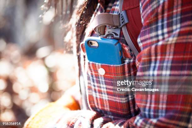 midsection of woman with smart phone in pocket - pocket stock-fotos und bilder