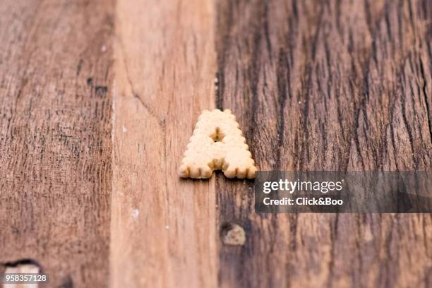 'a' cookie on a wooden surface - click&boo bildbanksfoton och bilder