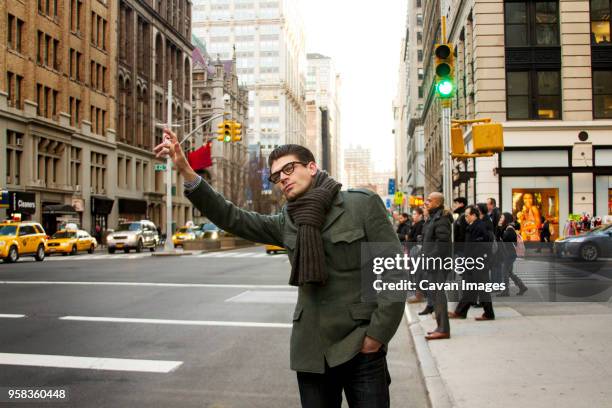 man hailing taxi on city street - hail stock-fotos und bilder