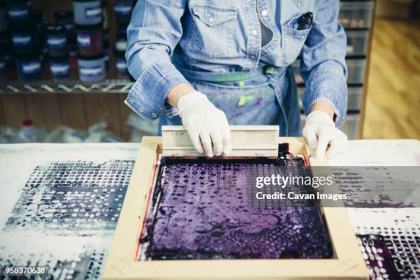 midsection of craftswoman using silk screen to print design on fabric at workshop - silk screen squeegee stock pictures, royalty-free photos & images