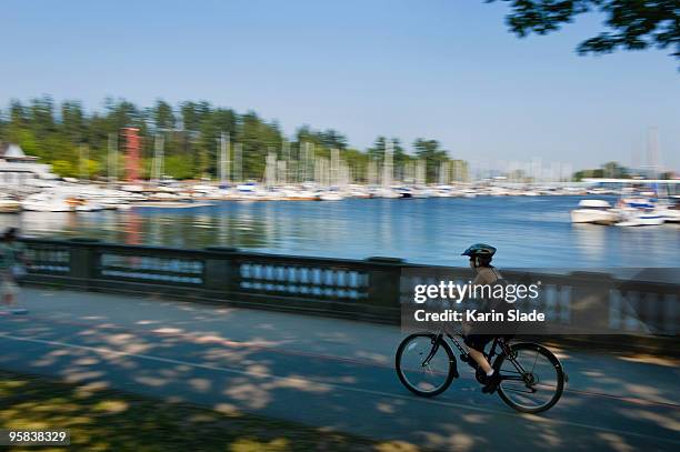 cyclist passes pleasure boats in a marina - coal harbor stock pictures, royalty-free photos & images