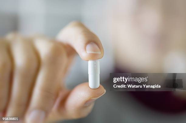 woman holding capsule - kapsel stock-fotos und bilder