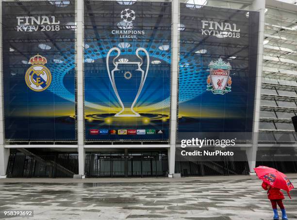 Kid under the umbrella walks past NSC Olimpiyskiy Stadium covered with banners for the Champions League in Kyiv, Ukraine, May 14, 2018. Kyiv prepares...