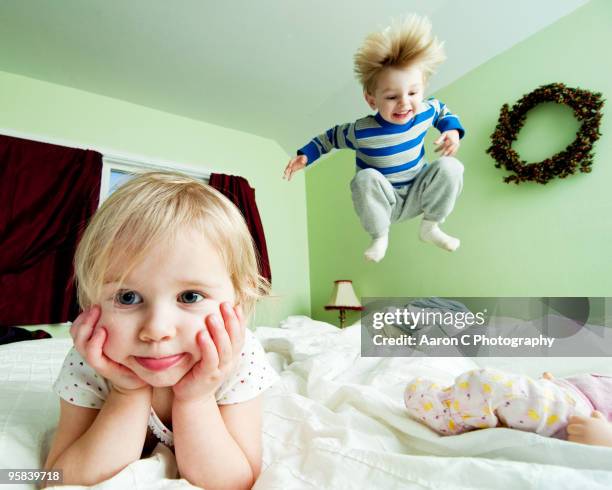 girl and boy jump on bed - children jumping bed stock-fotos und bilder