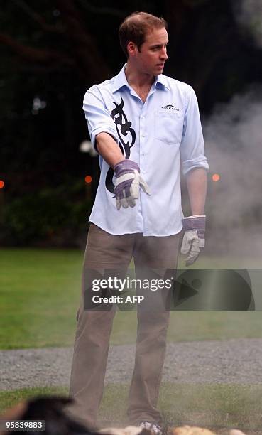 Britain's Prince William stands over a traditional Maori earth oven called a Hangi, at Government House on the second day of his visit on January 18,...