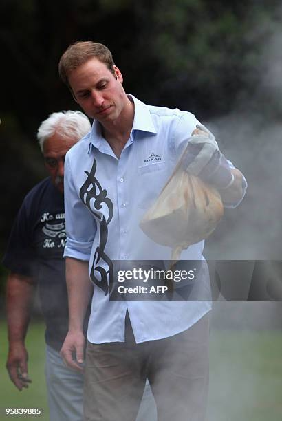 Britain's Prince William lifts a parcel of food out of the traditional Maori earth oven called a Hangi, at Government House on the second day of his...